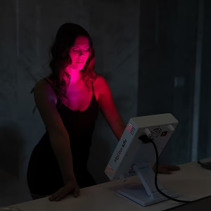 Woman in dark room focusing on red light therapy panel
