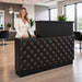 Woman standing behind black salon reception desk with black tuft in modern salon