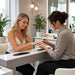 Nail tech working on woman's nails at manicure table in modern salon